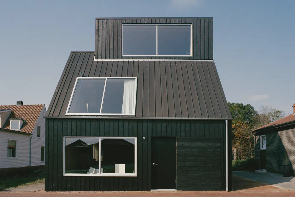 Woning met een donkere houten dakopbouw met grote ramen bovenop het platte dak
