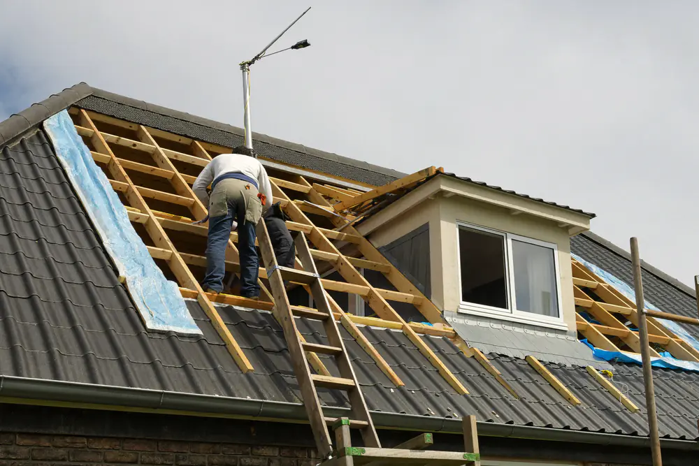 Timmerman bouwt op het dak een dakkapel, met het houten frame en de spanten zichtbaar