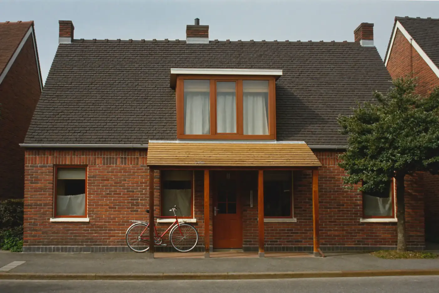 Bakstenen woning met pannendak en een houten dakkapel met drie ramen boven de voordeur