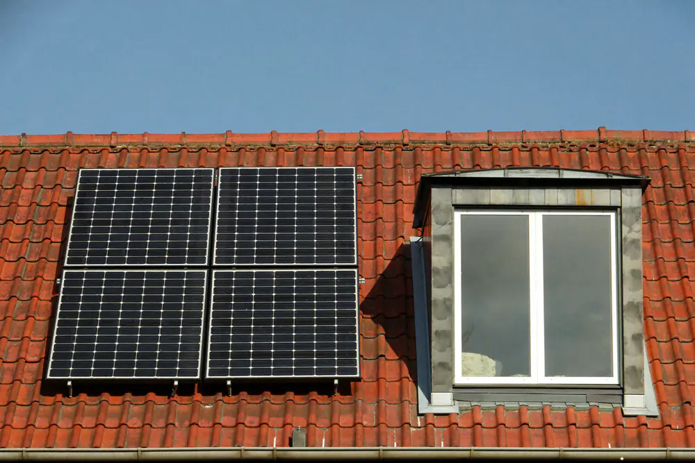 Pannendak met zonnepanelen naast een dakkapel met grijze bekleding